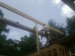 Carpenter setting a ridge beam over a new addition frame — Ice Dam Removal by Roofing Brothers in Durand
