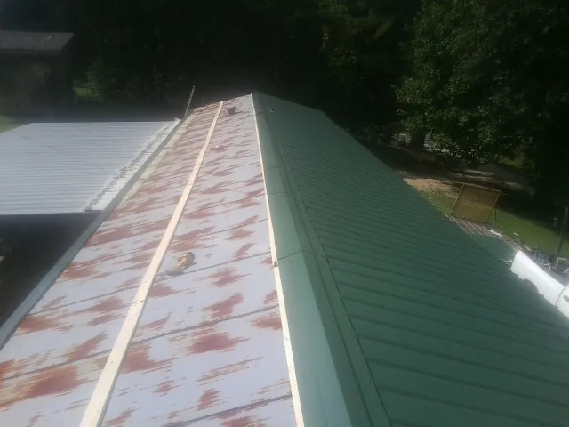 Old rusted panels beside newly installed green metal roofing — Wind Damage Roof Repair by Roofing Brothers in Durand