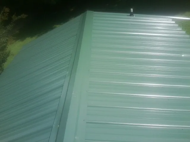New green metal panels meeting at the ridge of a roof — Flat Roof Repair work by our crew in Durand
