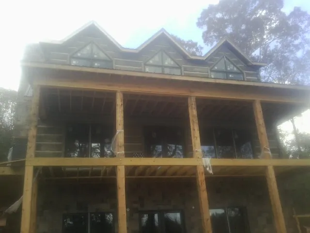 Dormers and porch framing on a large log home under construction — Roof Coating work by our crew in Durand