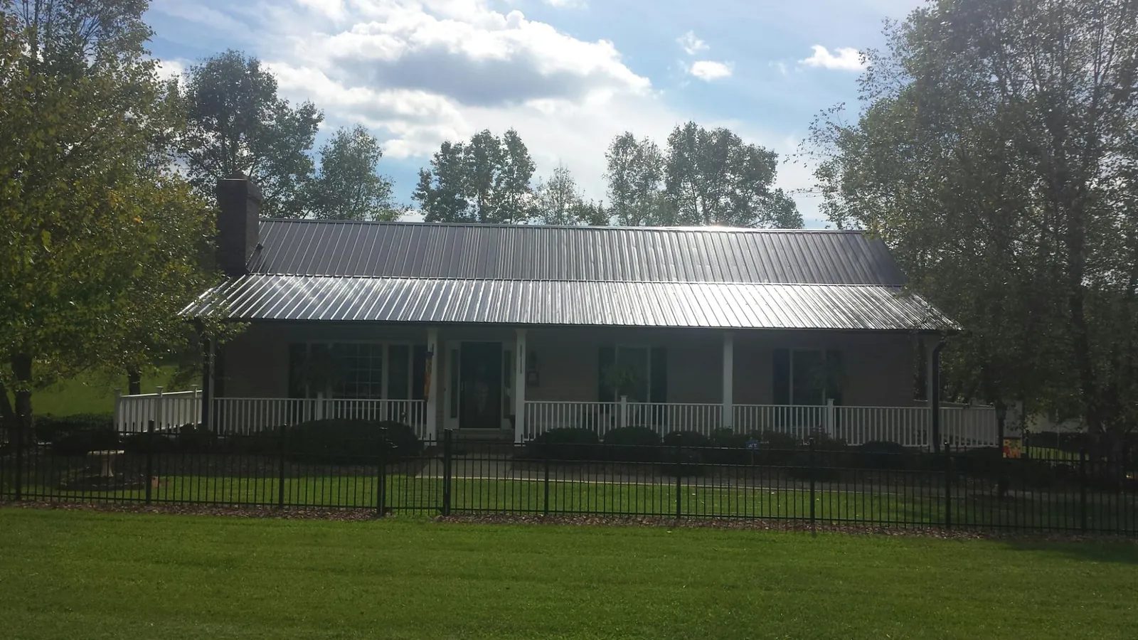 Gray metal roof on a brick ranch with a full width front porch — Gutter Guard Installation work by our crew in Durand